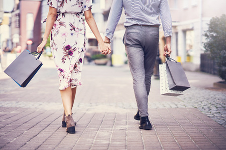 Portrait of happy couple with shopping bags in city smiling and huging.の写真素材