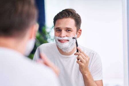 Portrait of adult man shaving in the bathroomの写真素材