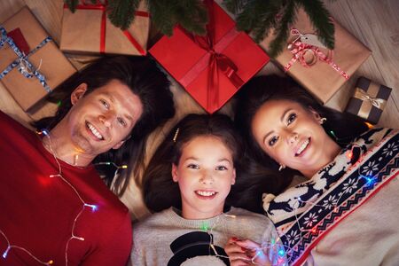 Beautiful family with presents under Christmas tree