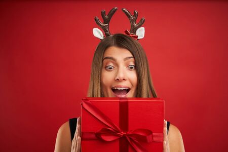 Adult happy woman with Christmas gift over red background