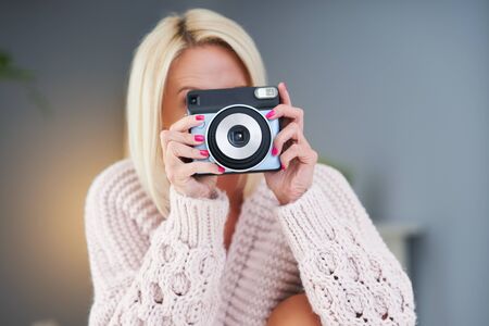 Adult beautiful woman taking instant photo at homeの写真素材