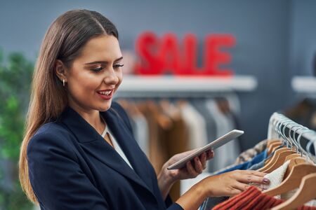 Happy shop assistant in her boutique with winter autumn collectionの写真素材