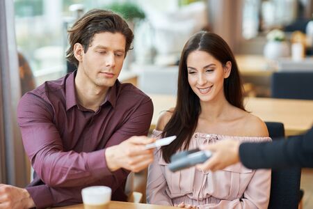 Young Couple paying by credit card in Cafe
