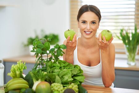 Healthy adult woman with green food in the kitchenの写真素材