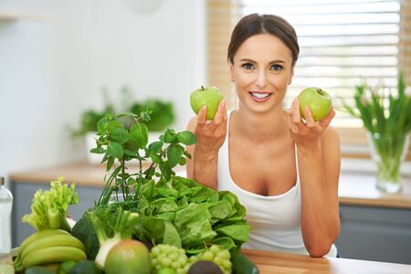 Healthy adult woman with green food in the kitchenの素材 [FY310141830360]