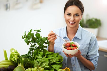 Healthy adult woman with green food in the kitchenの写真素材