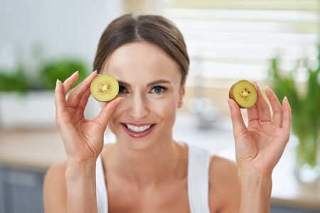 Healthy adult woman with green food in the kitchen