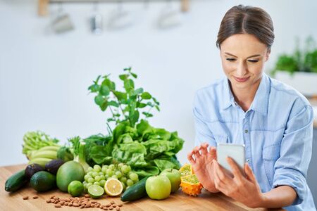 Healthy adult woman with green food in the kitchenの写真素材