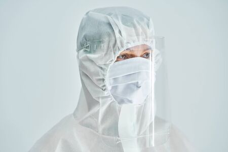 Woman in bio-hazard suit and face shield on white background.の写真素材