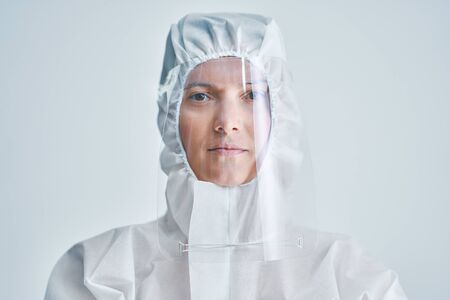 Woman in bio-hazard suit and face shield on white background.の写真素材
