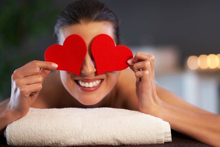 Relaxed woman waiting for a back massage and holding heartの写真素材