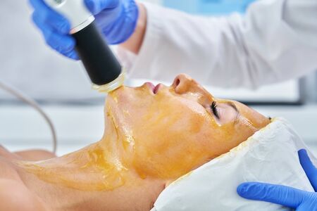 Beautiful young woman getting face treatment at beauty salon.