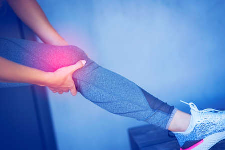 Midsection of female runner holding knee in painの写真素材