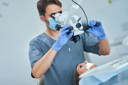 Dentist checking up patient teeth with microscope at surgery officeの写真素材