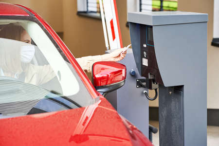 Woman getting ticket from parking meter in underground parking