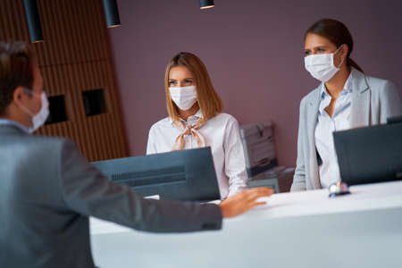 Businessman in mask at the reception of a hotel checking inの写真素材