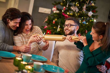Group of friends celebrating Christmas by pulling crackersの写真素材