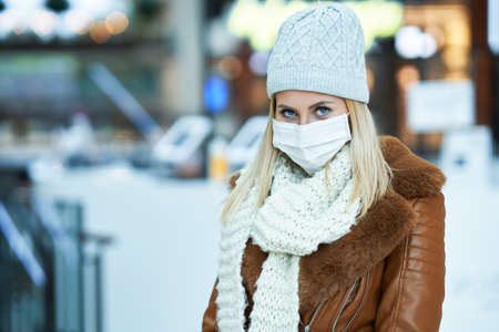 Portrait of adult woman shopping in mall wearing a mask, coronavirus concept