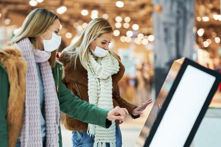 Portrait of two friends shopping together wearing a mask, coronavirus concept