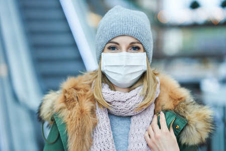 Portrait of adult woman shopping in mall wearing a mask, coronavirus conceptの写真素材