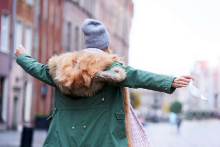 Woman taking off face mask in the cityの写真素材