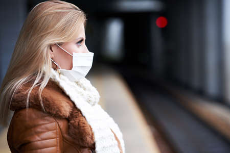 Adult woman at train station wearing masks due to covid-19 restrictionsの写真素材