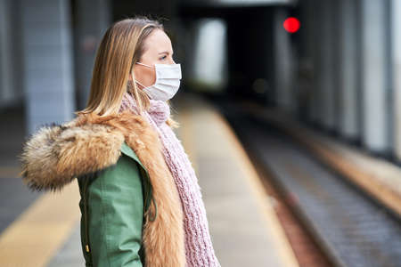 Adult woman at train station wearing masks due to covid-19 restrictionsの写真素材