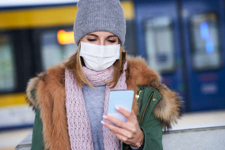 Adult woman at train station wearing masks due to covid-19 restrictions