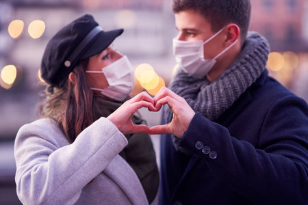 Happy couple celebrating Valentines Day in masks during covid-19 pandemicの写真素材