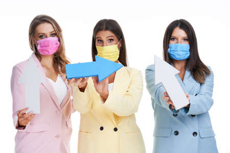 Three women in pastel suits posing with arrows over white backgroundの写真素材
