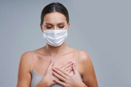 Portrait of beautiful woman in mask on gray backgroundの写真素材