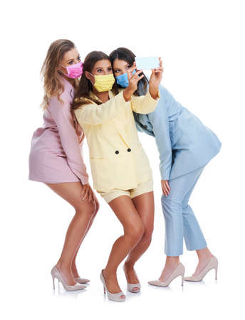 Three women in pastel suits posing with smartphones over white backgroundの写真素材