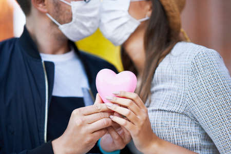 Adult romantic couple wearing masks on the walk in the city