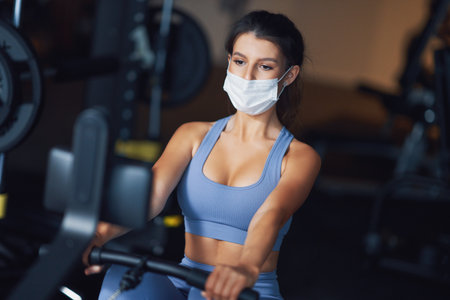 Adult woman working out in a gym in mask