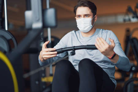 Adult man working out in a gym wearing mask