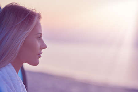 Silhouette of young woman practicing yoga on the beach at sunriseの写真素材