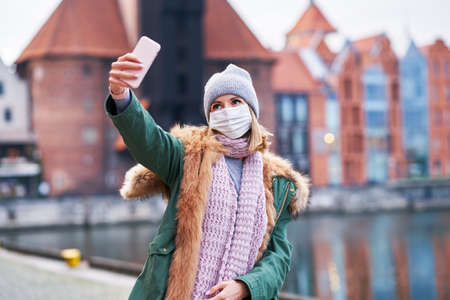 Woman wearing face mask and taking selfie in the city