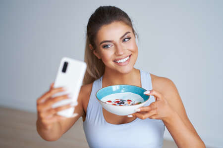 Portrait of beautiful hispanic woman eating yoghurt promoting healthy lifestyleの写真素材