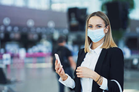 Adult female passenger using smartphone at the airportの写真素材