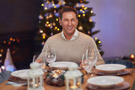 Man sitting alone by the christmas tableの写真素材