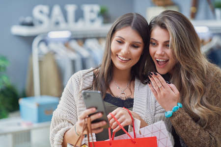 Group of happy friends during shopping with phoneの写真素材