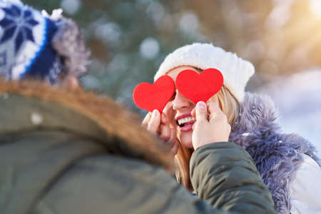 Couple with red hearts in winter snowy scenery