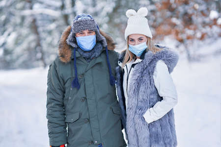 Young couple having fun on snow wearing maskの写真素材
