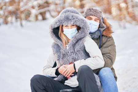Young couple having fun on snow wearing maskの写真素材
