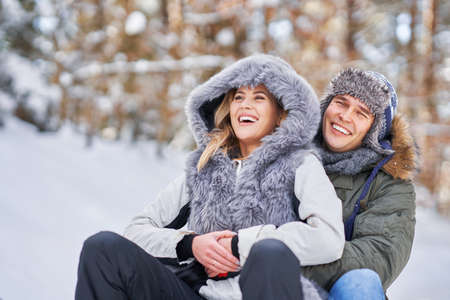 Couple having fun with sledge on snow in winterの写真素材