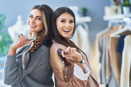 Two happy girls on shopping holding shoesの写真素材