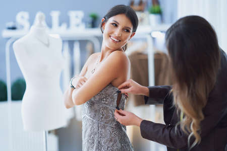 Woman in dress in clothes store with tailorの写真素材