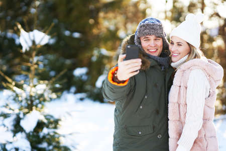 Young couple having fun on snow taking selfieの写真素材
