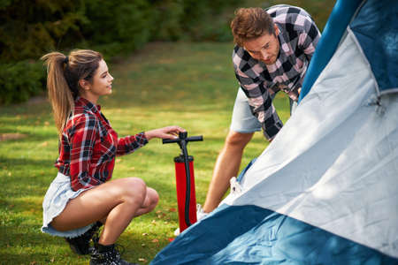 Young nice couple having fun on camping setting up tentの写真素材