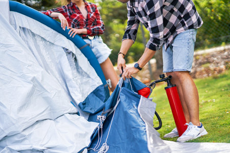 Young nice couple having fun on camping setting up tentの写真素材
